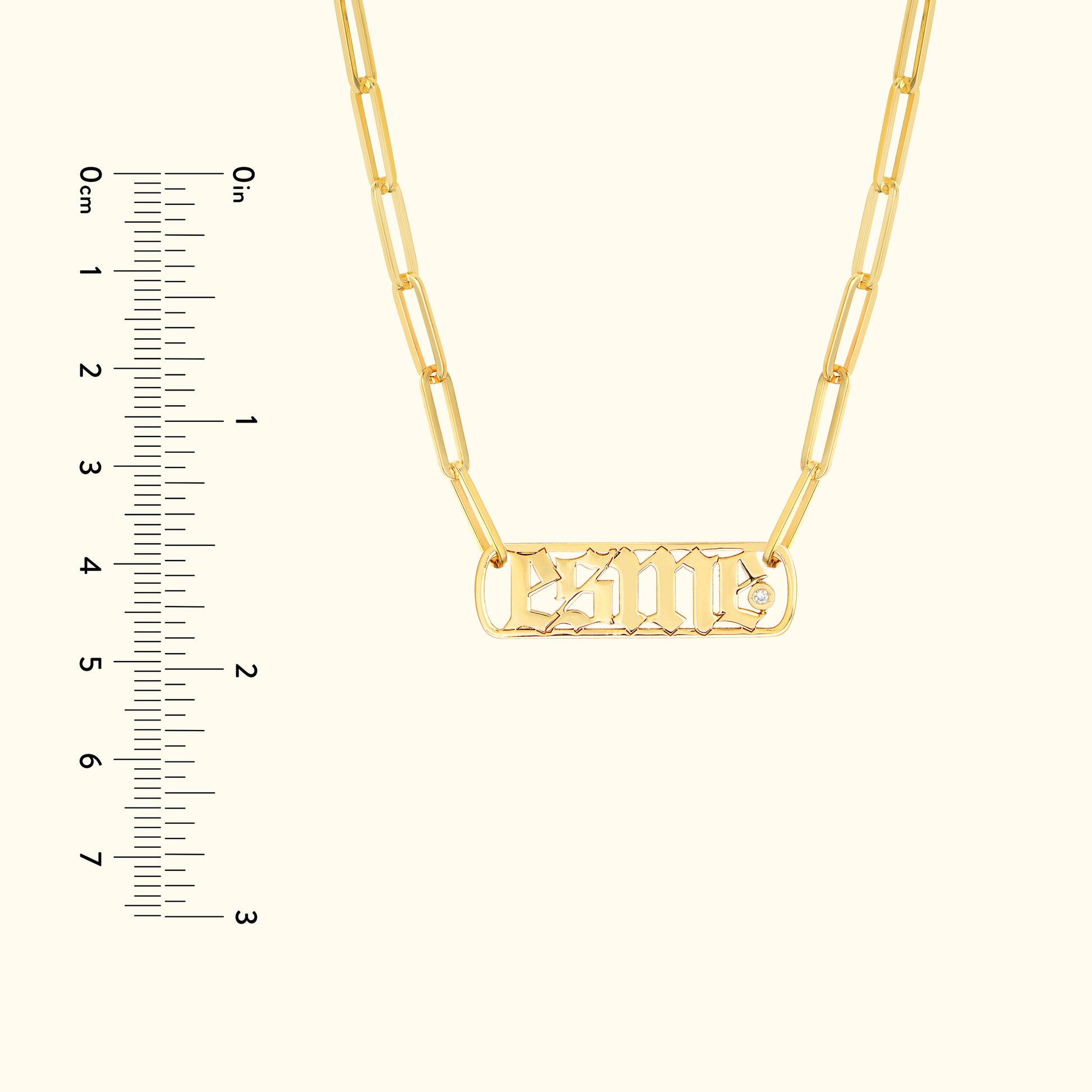 Gold necklace with a chain and a rectangular pendant featuring engraved letters.