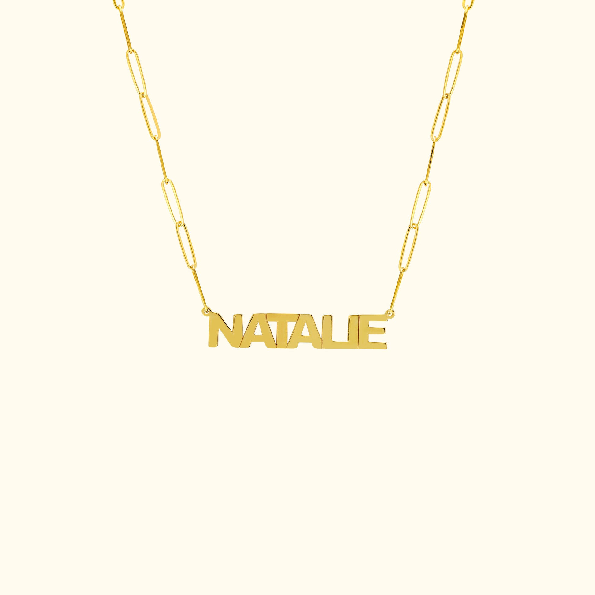 Gold name necklace with the word "NATALIE" in a bold font on a linked chain.