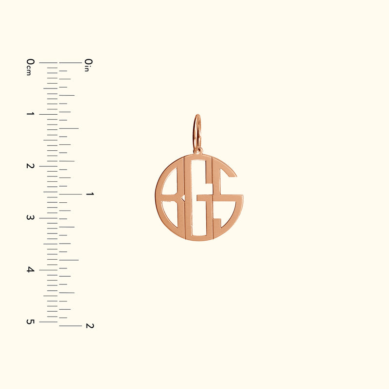 Rose gold monogram pendant with an open design, accompanied by a ruler for size reference.