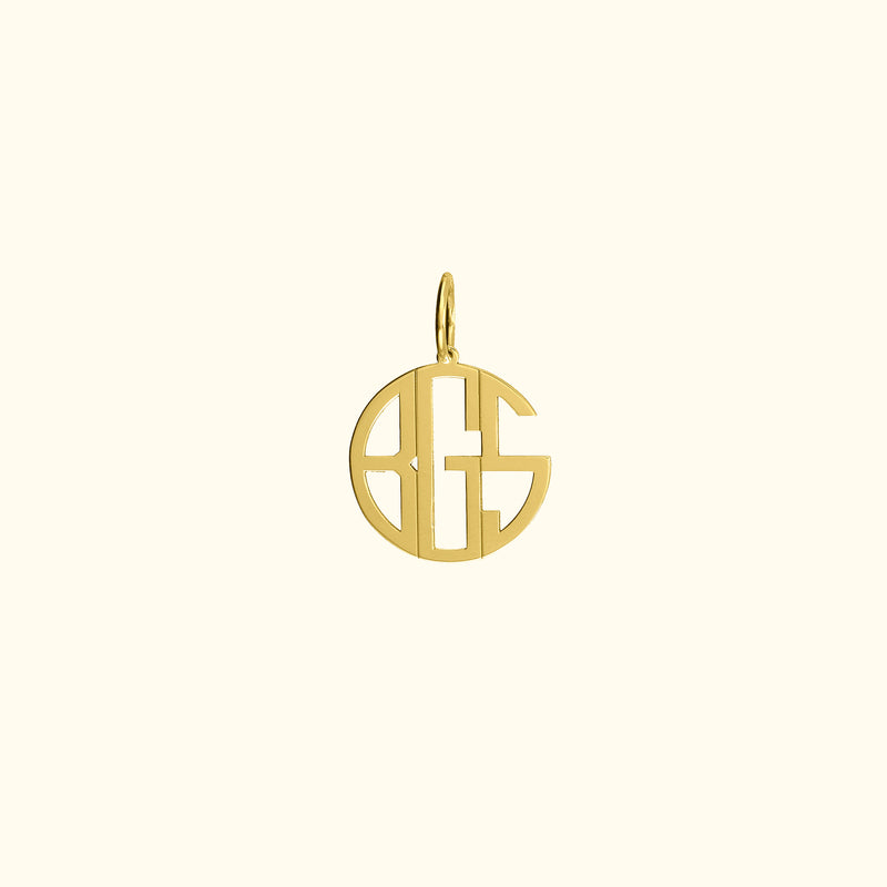 Gold pendant featuring a stylized monogram within a circular design.