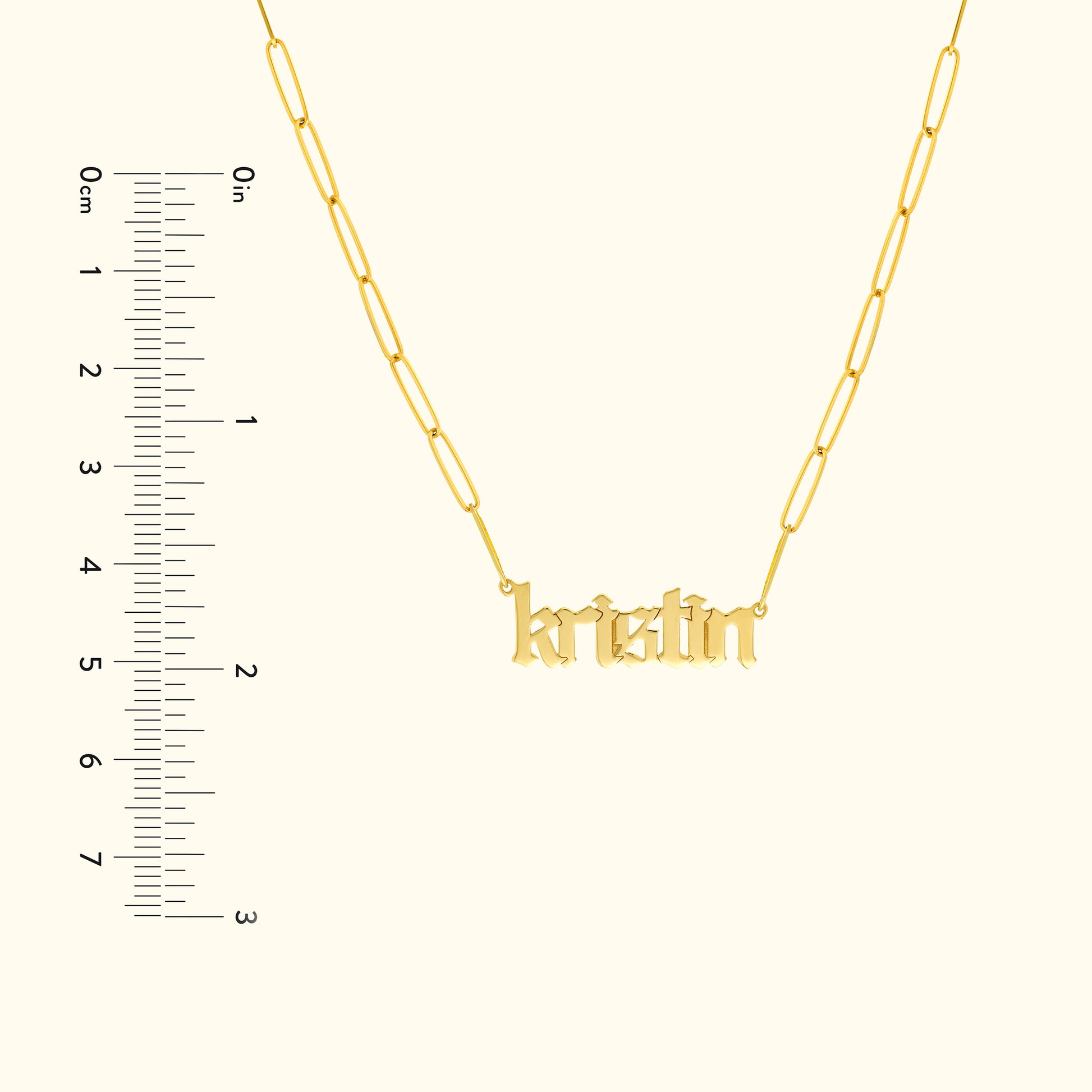 Gold necklace with a nameplate reading "kristin," displayed with a ruler for size reference.