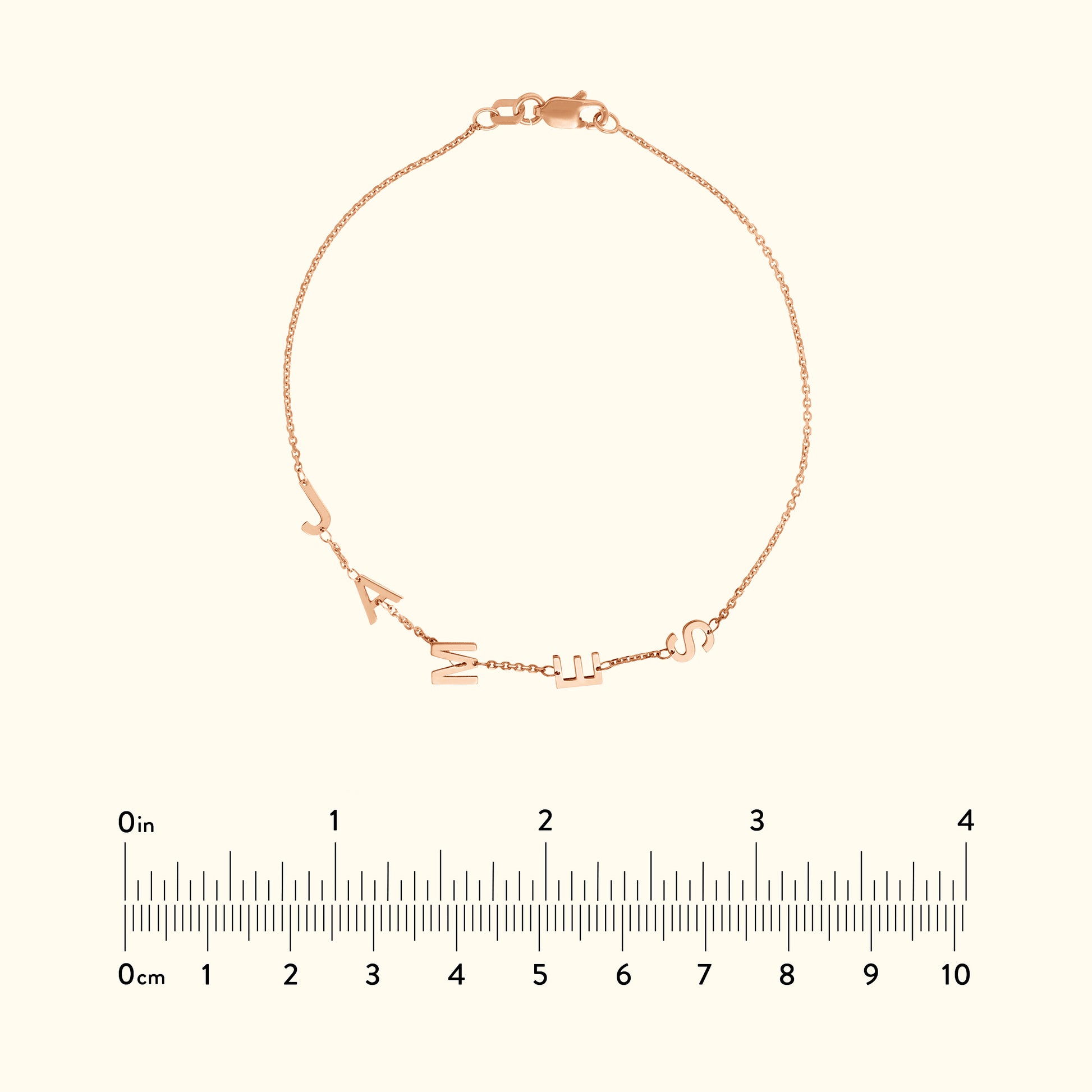 Rose gold bracelet with letters spelling "J A N I S" attached to a delicate chain.