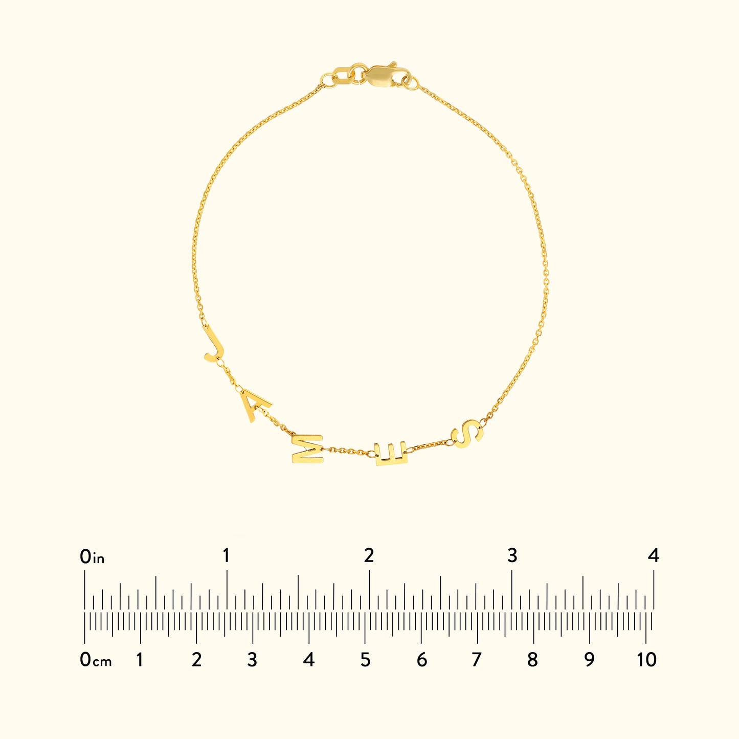 Gold bracelet featuring alphabet charms, displayed with a ruler for size reference.