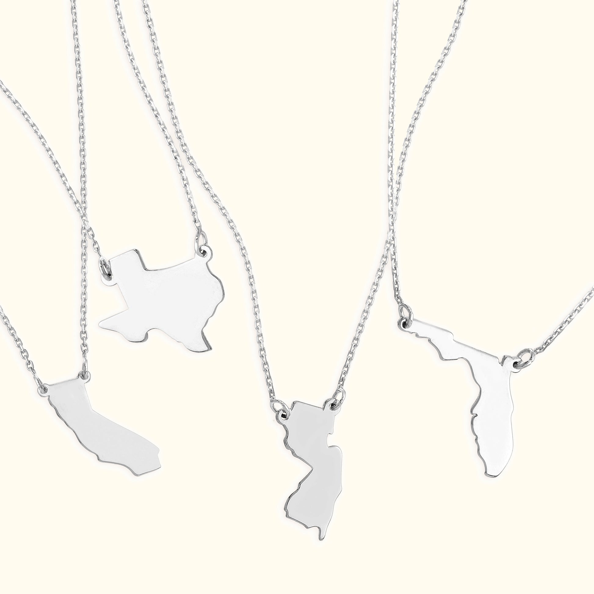 Silver necklaces featuring state-shaped pendants.