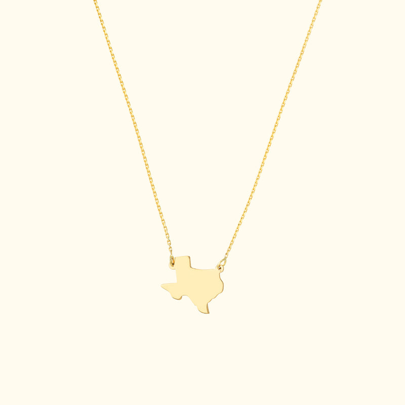 Gold necklace featuring a Texas state outline pendant on a delicate chain.
