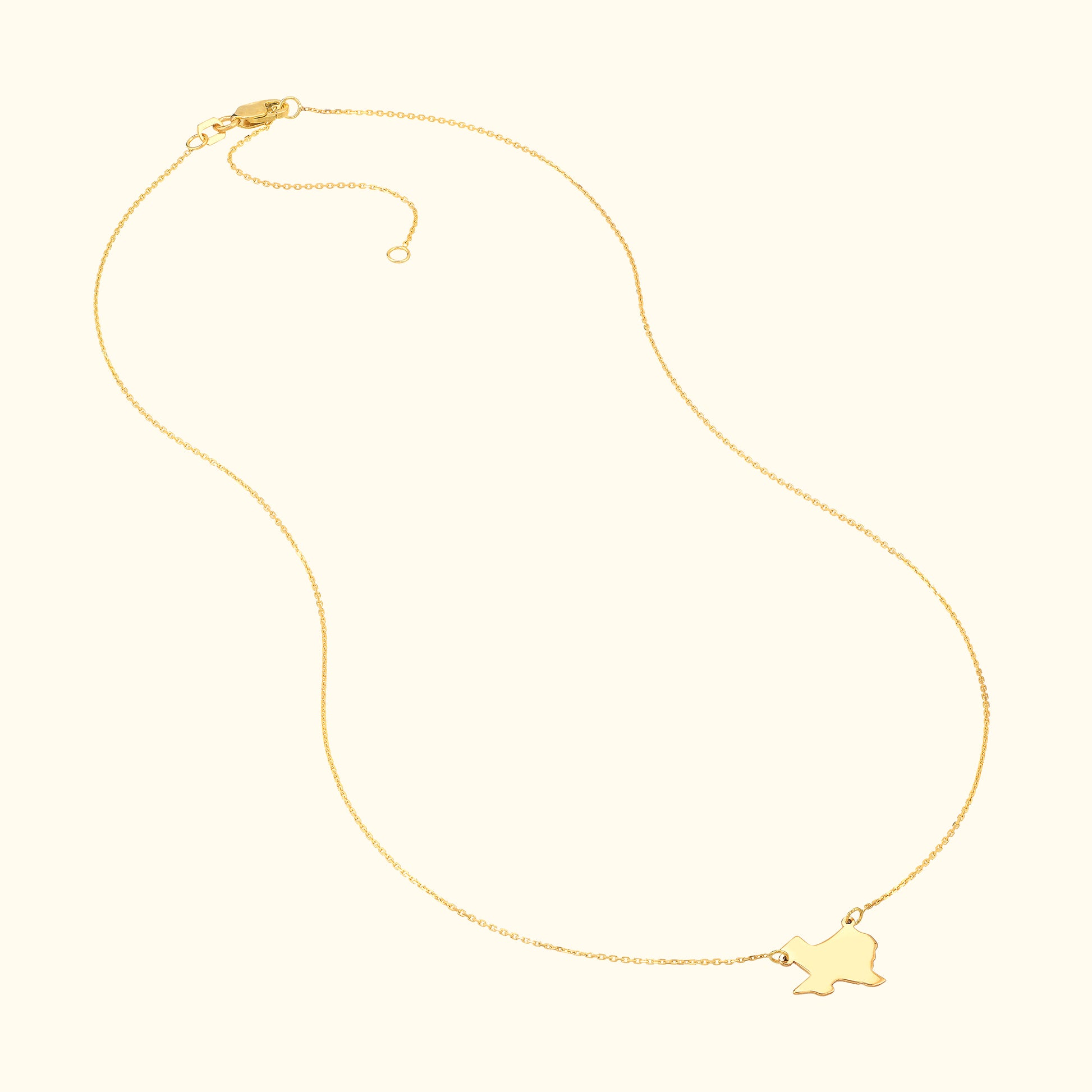 Gold necklace with a delicate chain and a small charm in the shape of a bird.