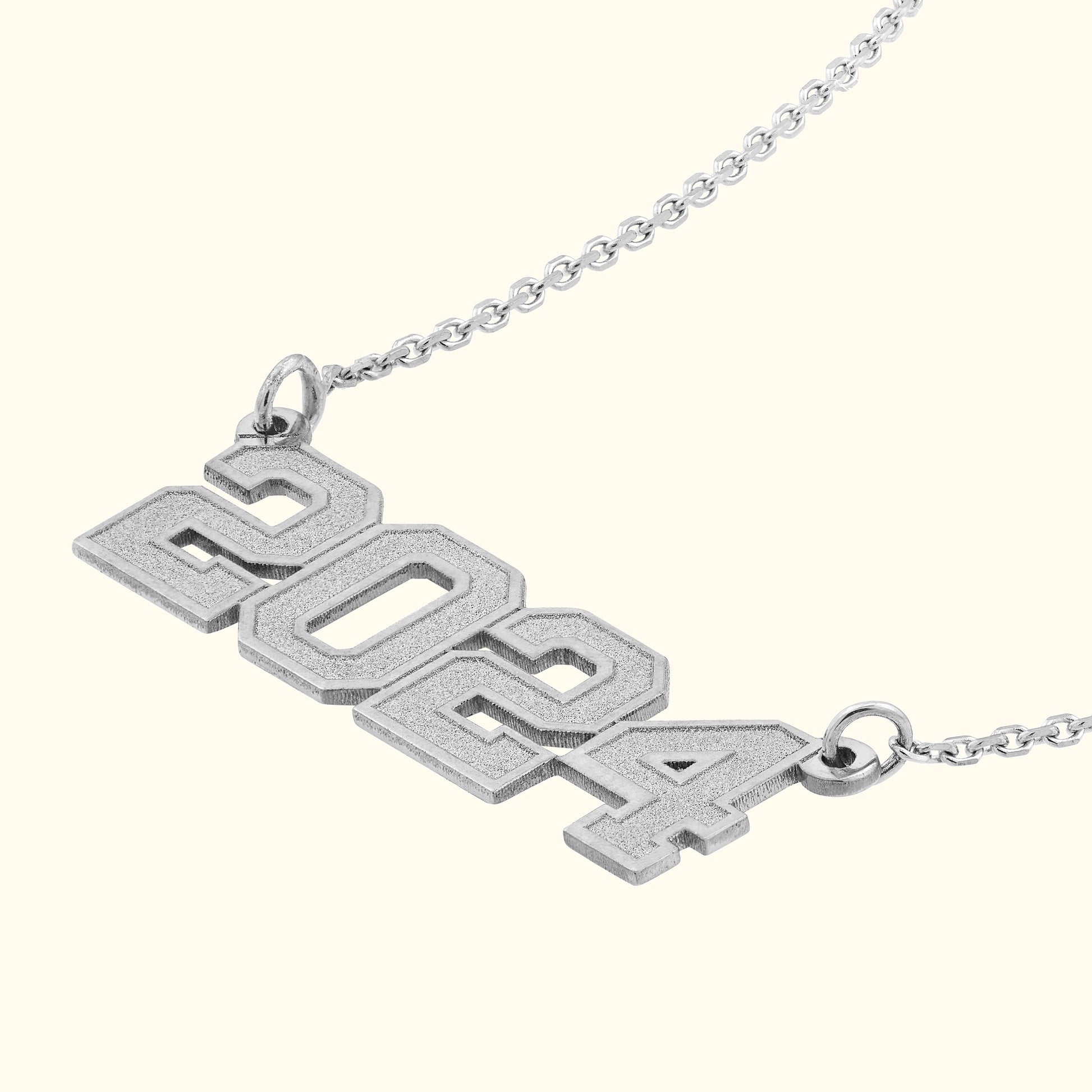 Silver pendant necklace featuring the year "2024" in bold, block letters.