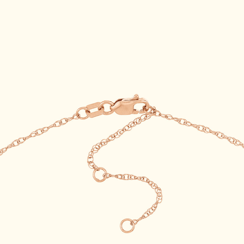 Close-up of a delicate rose gold chain with a clasp and adjustable length.