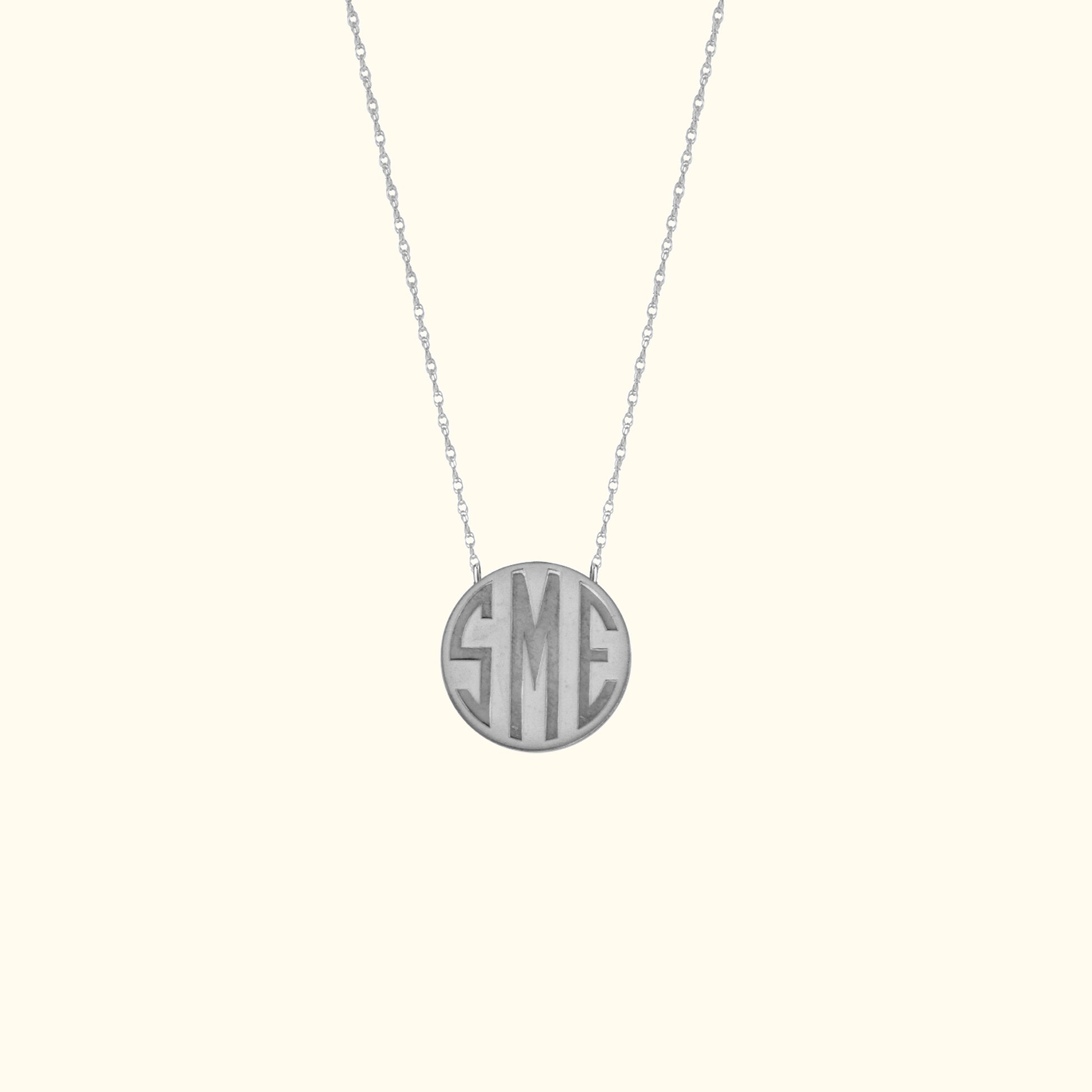 Monogrammed silver pendant necklace on a delicate chain.