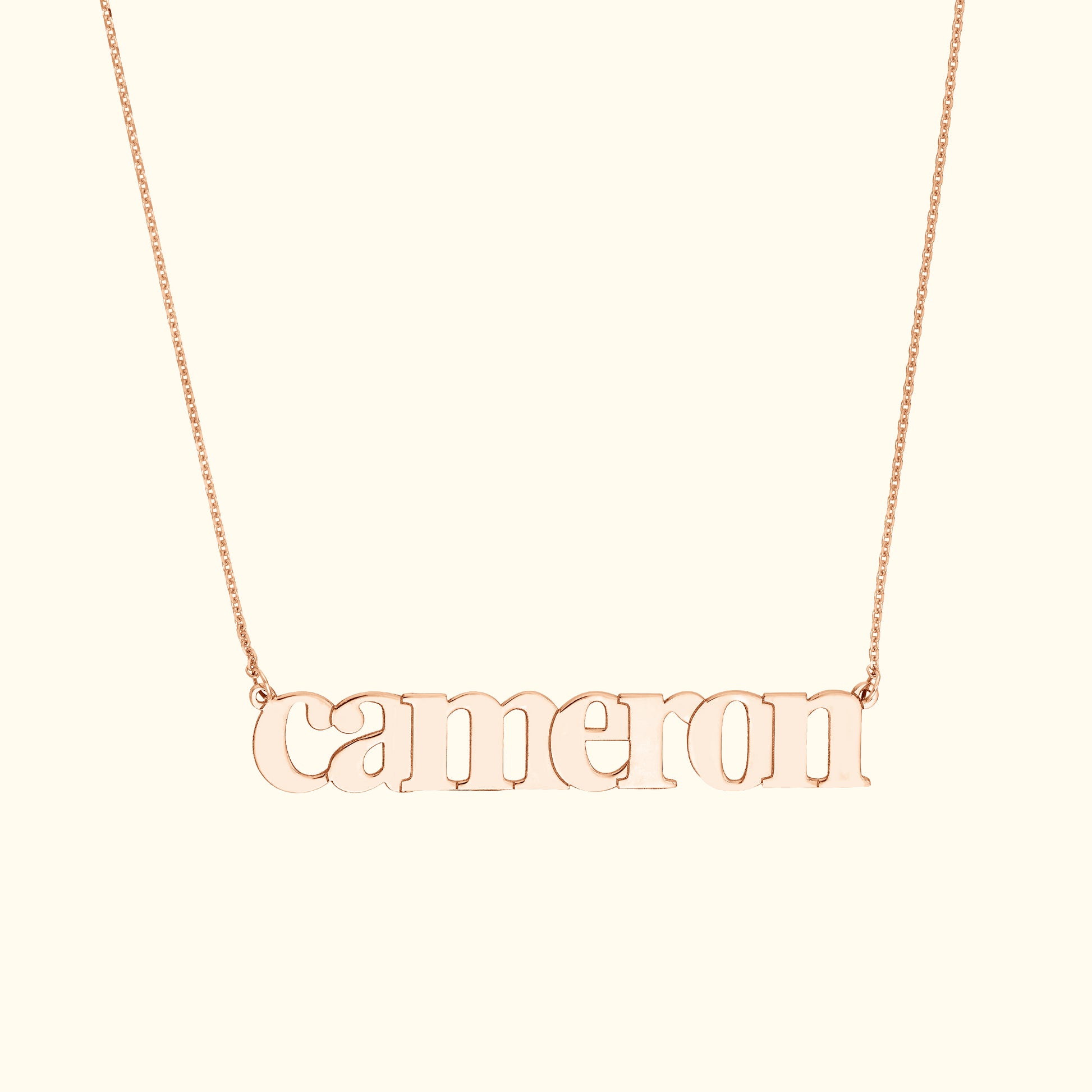 Rose gold name necklace featuring the word "cameron" in a playful font.