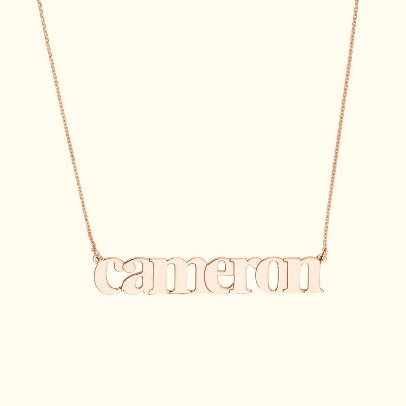 Rose gold name necklace featuring the word "cameron" in a playful font.