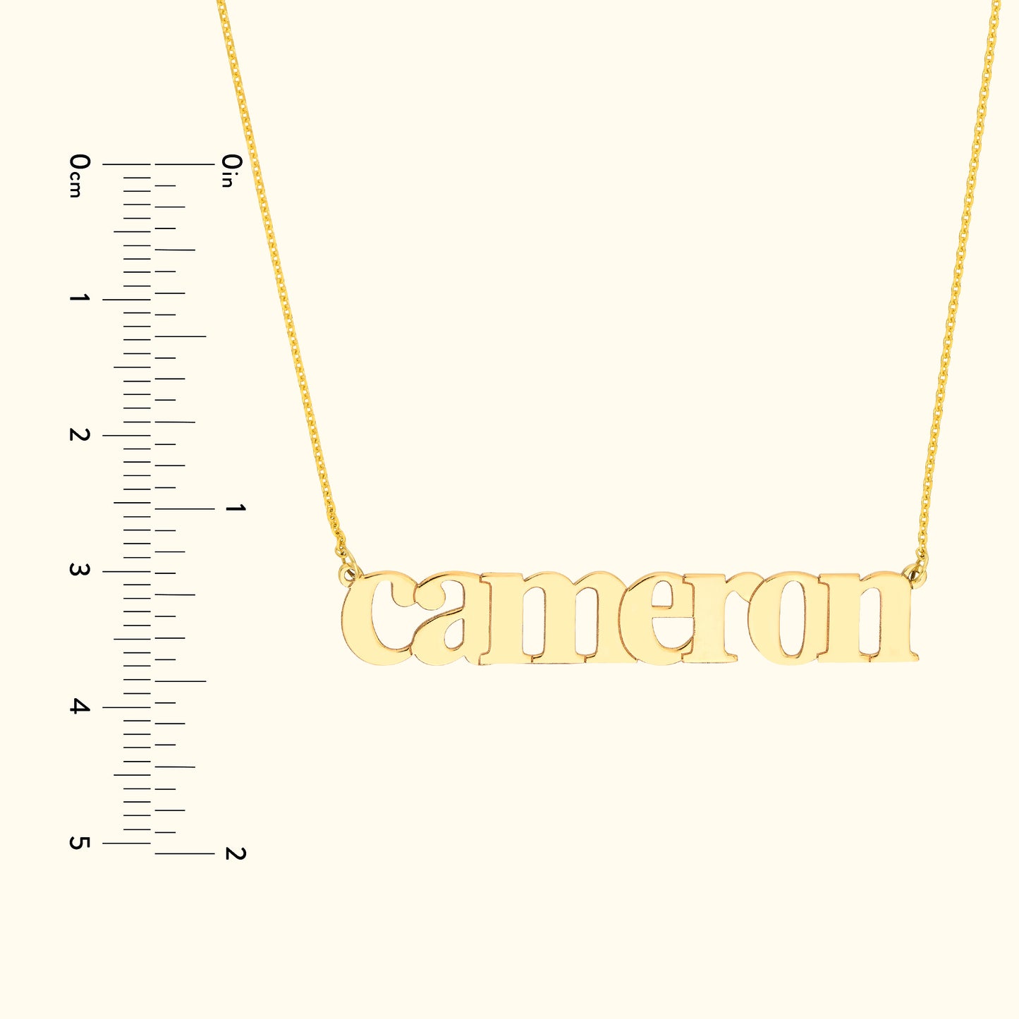 Gold name necklace spelling "cameron" on a simple chain with a ruler for size reference.