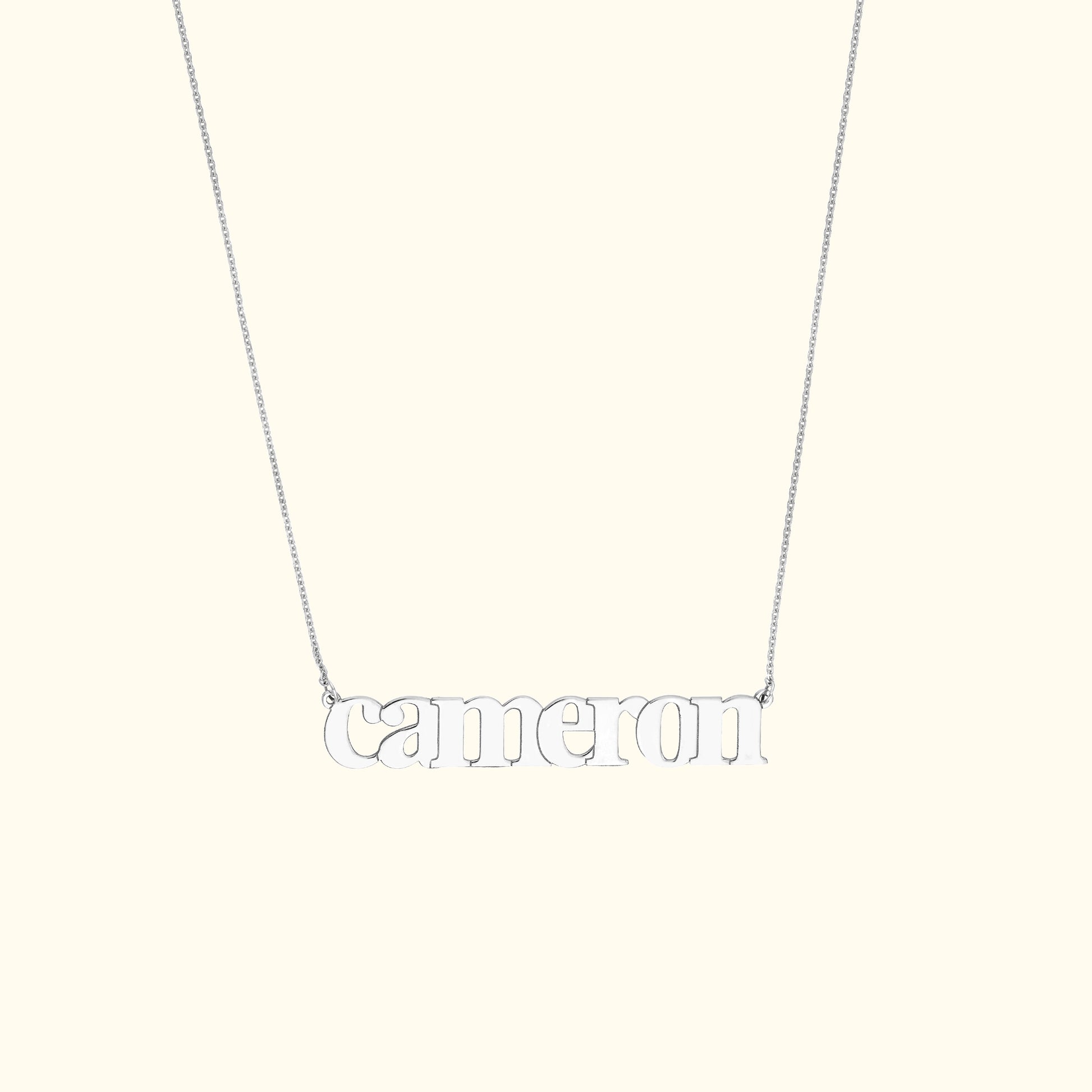 Silver name necklace reading "cameron" on a delicate chain.