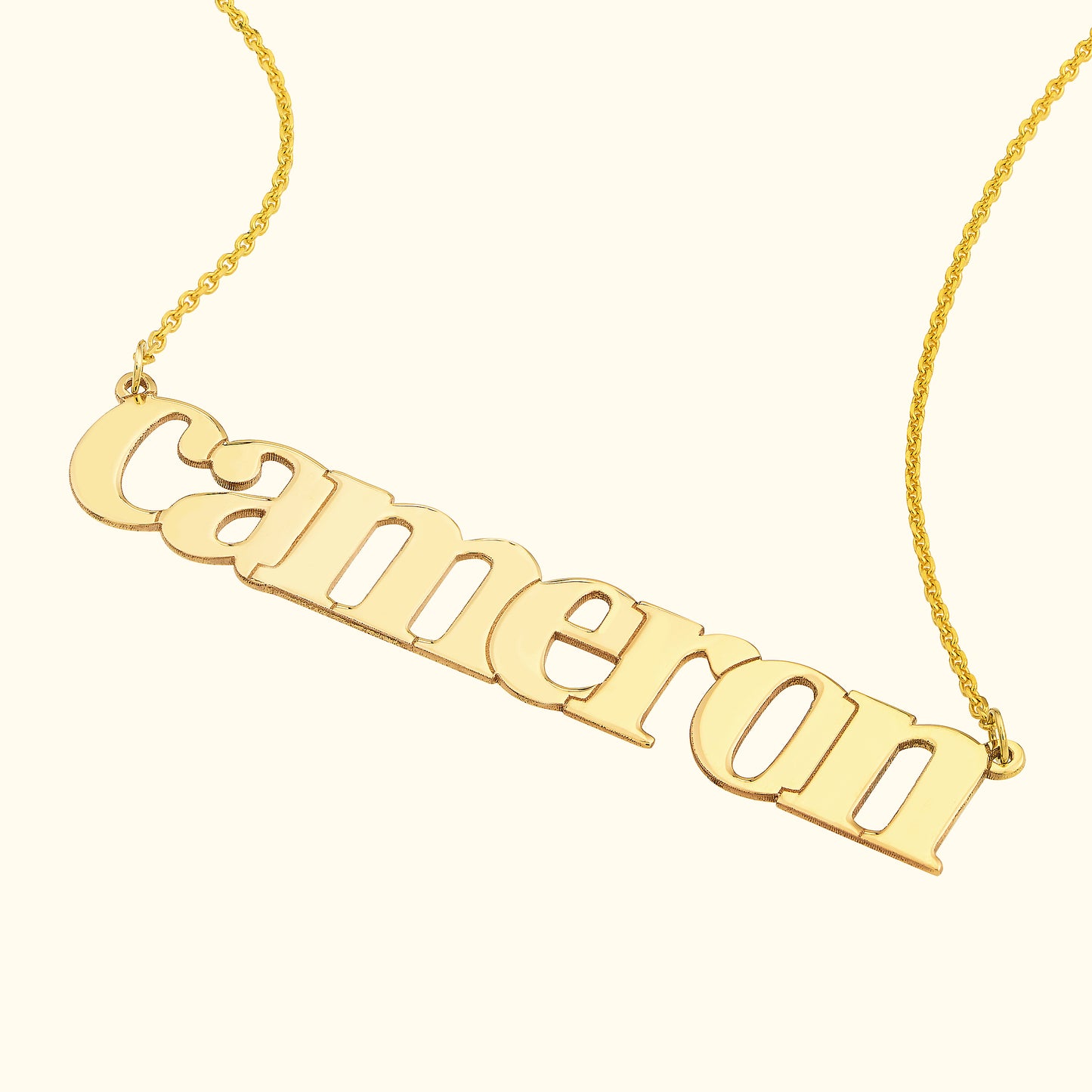Gold name necklace with the inscription "cameron" displayed on a light background.