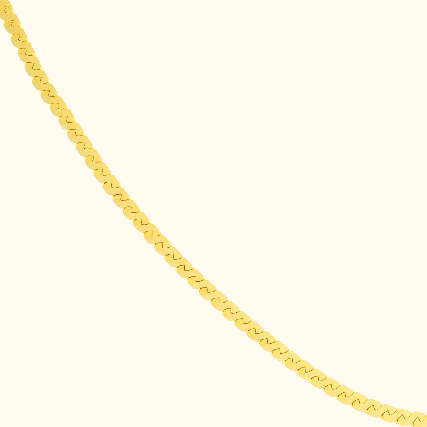 Gold chain necklace with a wavy link design against a light background.
