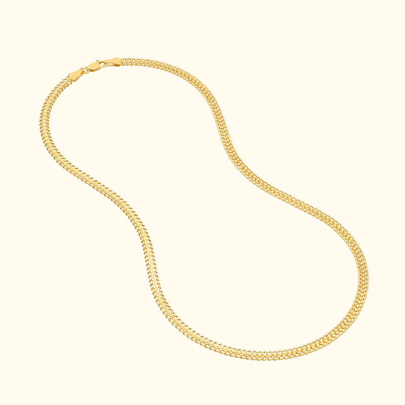 Gold chain necklace with a sleek, curved design on a light background.