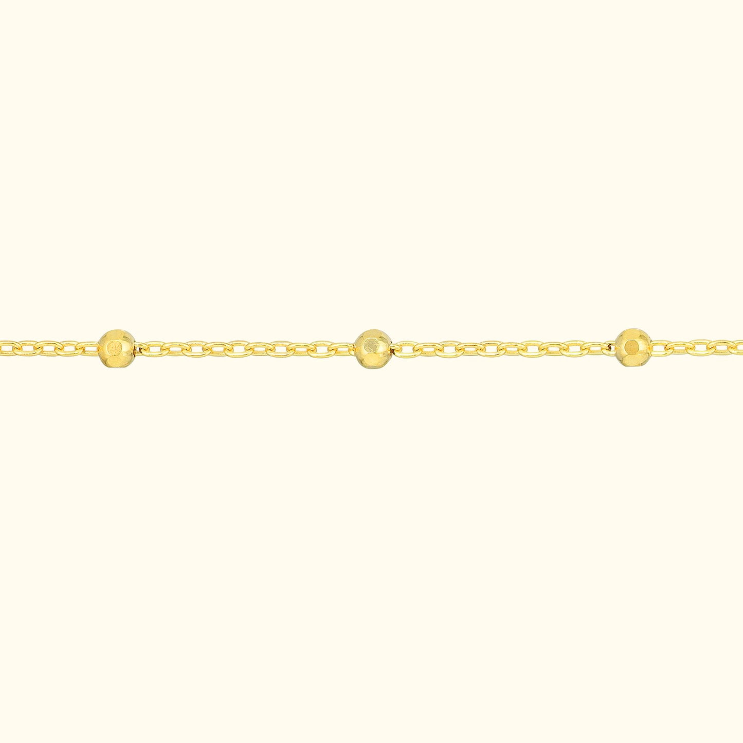 Delicate gold chain necklace adorned with small round beads.