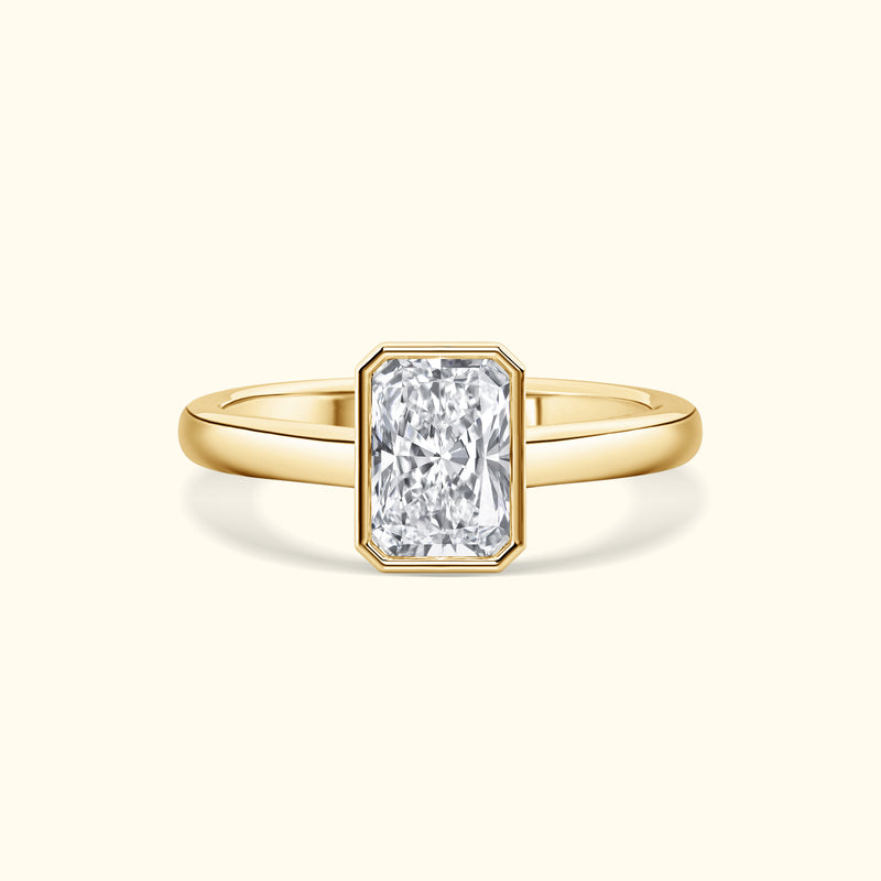 A gold ring featuring a large rectangular diamond in a simple, elegant setting.