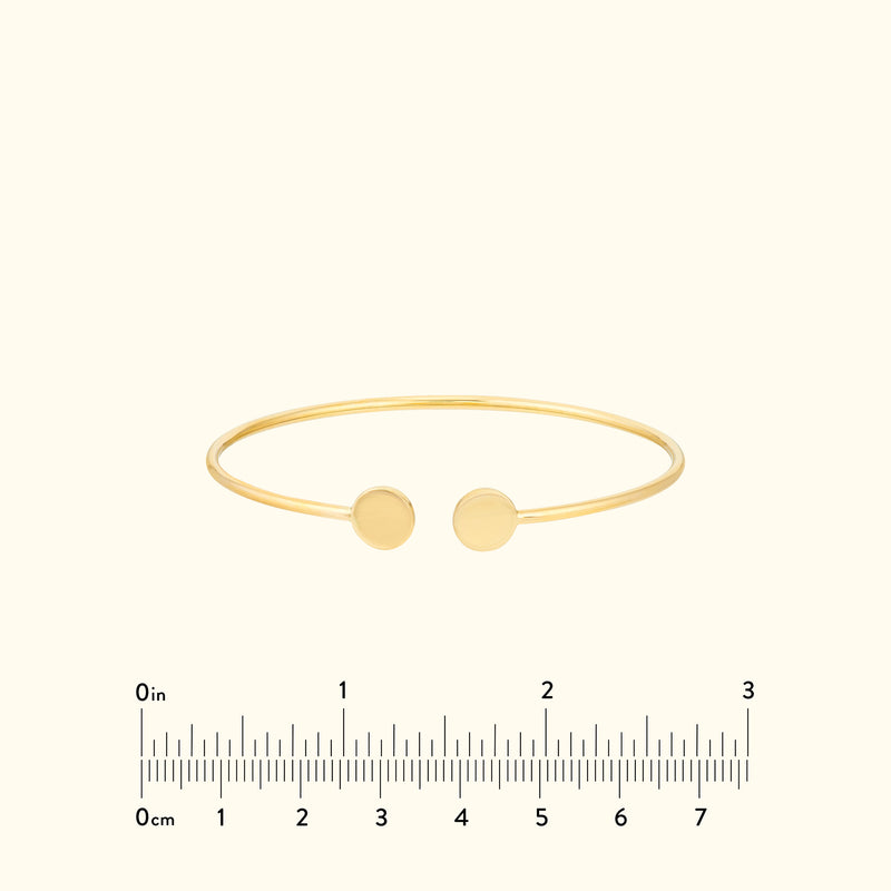 Minimalist gold cuff bracelet with two circular ends.