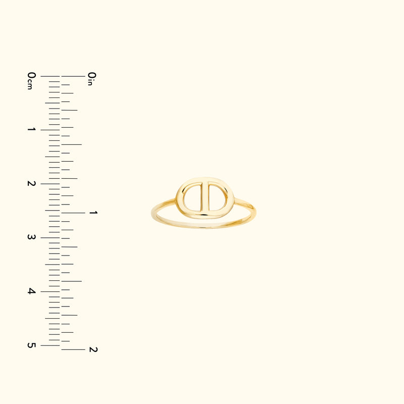 Simple gold ring with an oval design, placed against a light background with a ruler.