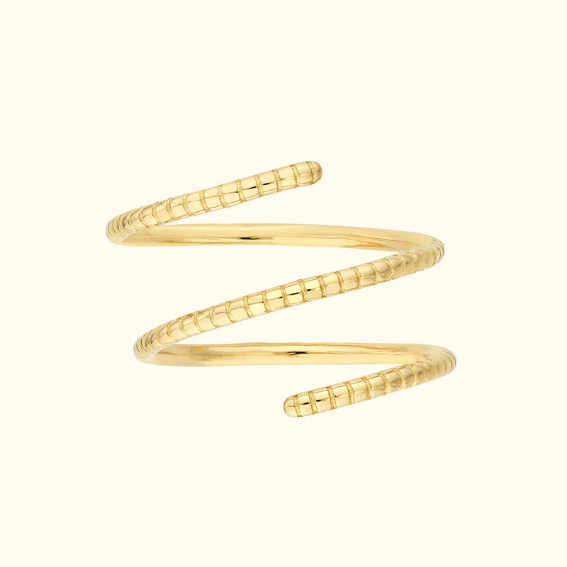 Spiral gold ring with textured design, set against a light background.