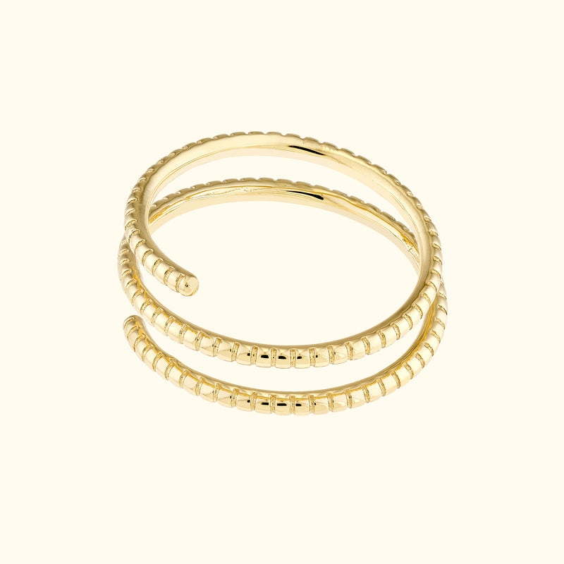Three intertwined gold rings with textured bands on a light beige background.