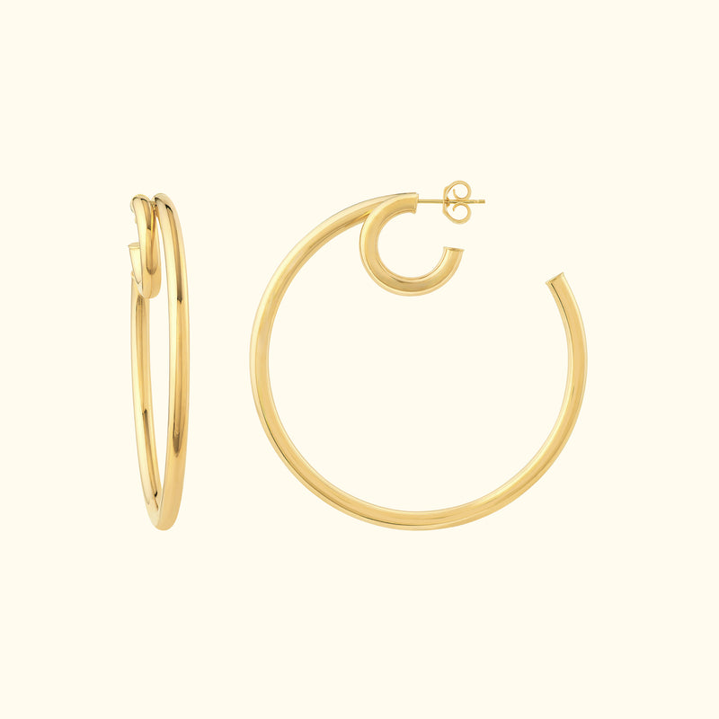 Two gold hoop earrings, one smaller and the other larger, set against a light background.