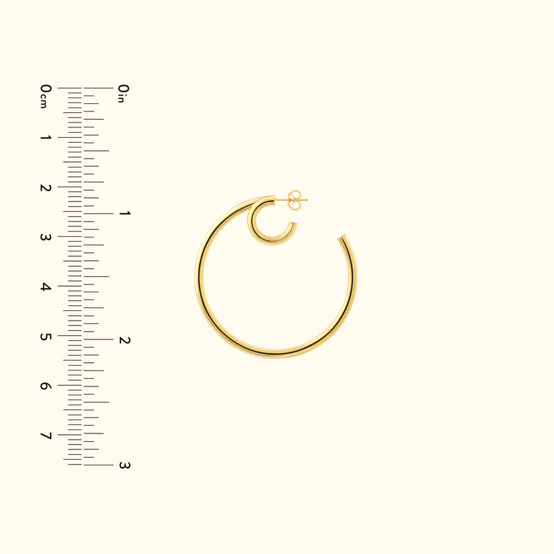 Gold hoop earring displayed next to a ruler for size reference.