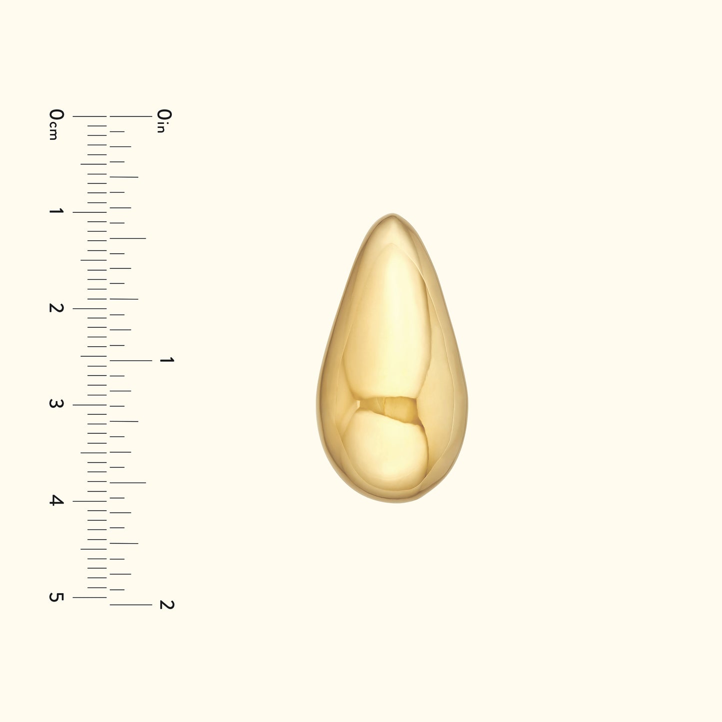 Polished gold teardrop pendant on a neutral background with a measuring scale.