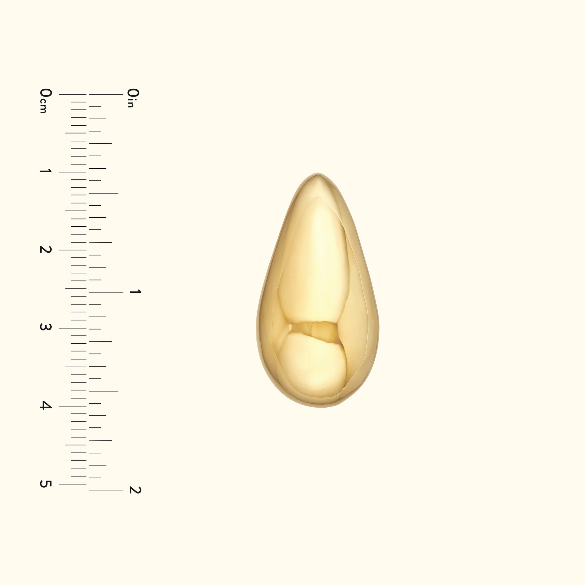 Polished gold teardrop pendant on a neutral background with a measuring scale.