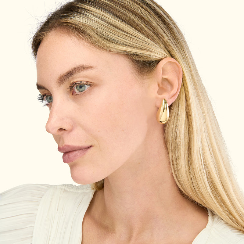Gold teardrop earrings worn by a woman with long, straight blonde hair.