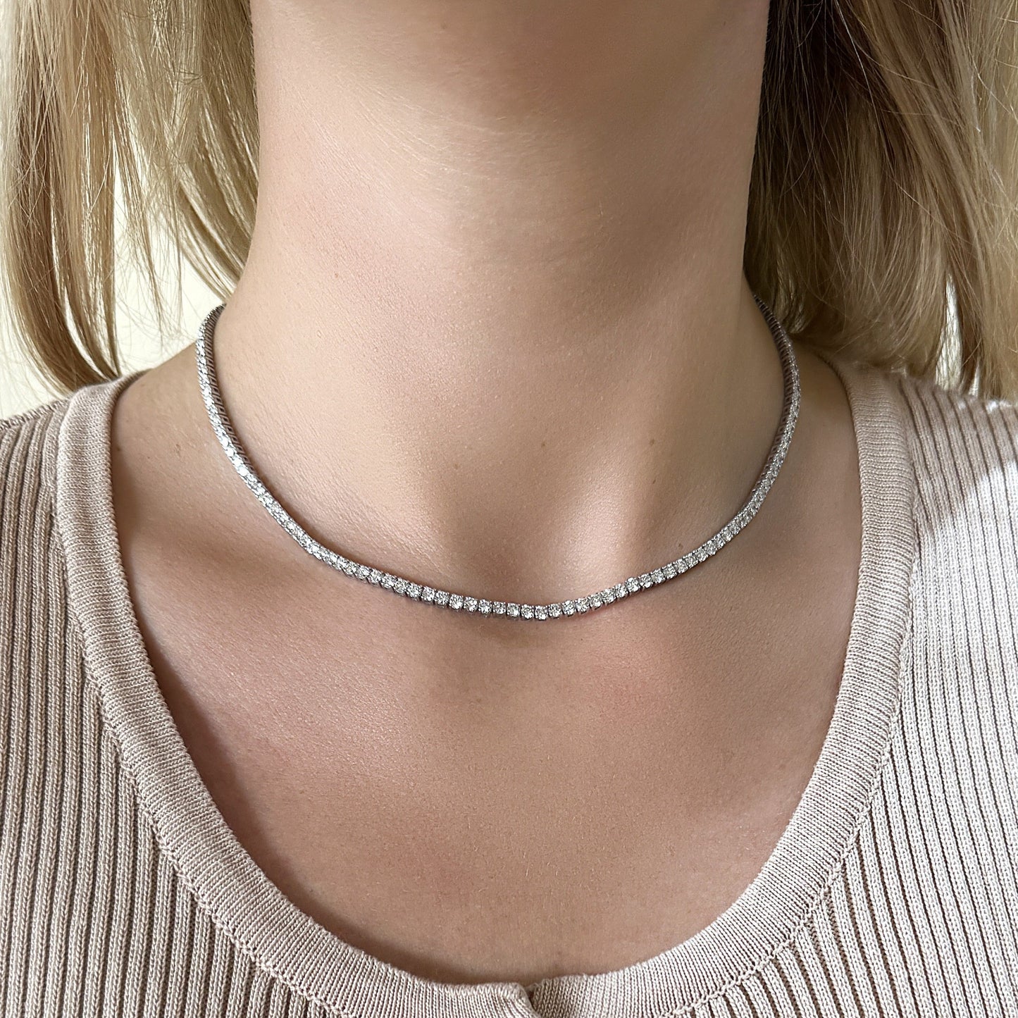 A close-up of a woman wearing a sparkling diamond choker necklace.