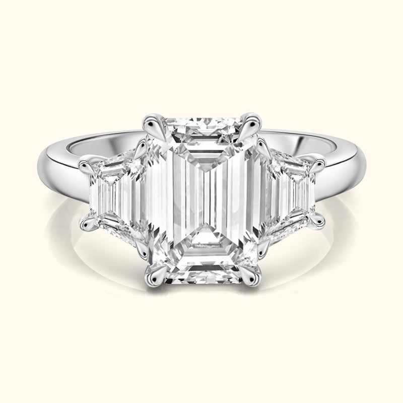 Elegant three-stone ring featuring a central emerald-cut diamond flanked by smaller diamonds.
