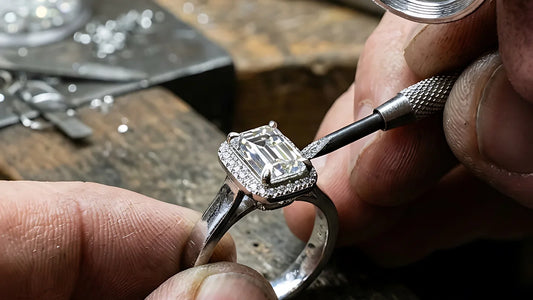 Jeweler setting an emerald-cut diamond halo engagement ring at the bench