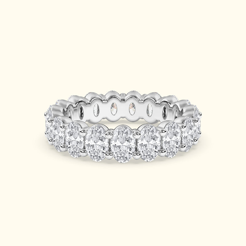 Elegant white gold band adorned with oval-shaped diamonds, featuring intricate detailing.