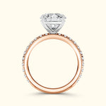 Rose gold engagement ring with a diamond halo setting and a large central gemstone.