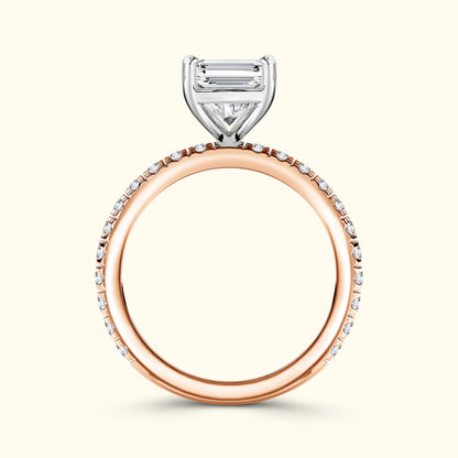 Rose gold engagement ring with a diamond band and a prominent three-stone setting.