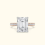 Emerald-cut diamond ring with a rose gold band and smaller diamonds along the shank.