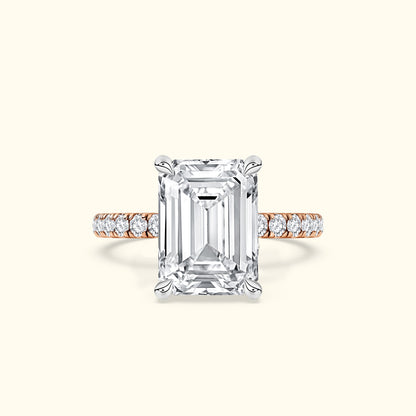 Emerald-cut diamond ring with a rose gold band and smaller diamonds along the shank.