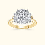 A gold and platinum ring featuring a large central diamond flanked by two smaller diamonds.
