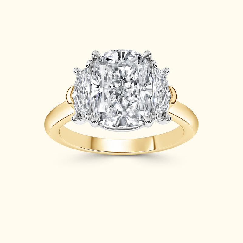 A gold and platinum ring featuring a large central diamond flanked by two smaller diamonds.