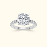 A solitaire diamond ring with a round center stone and smaller diamonds on the band.