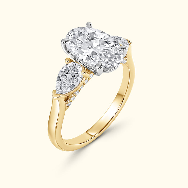 Elegant gold ring featuring a central oval diamond and two pear-shaped side diamonds.