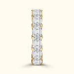 Gold band set with alternating emerald-cut diamonds, vertically oriented.