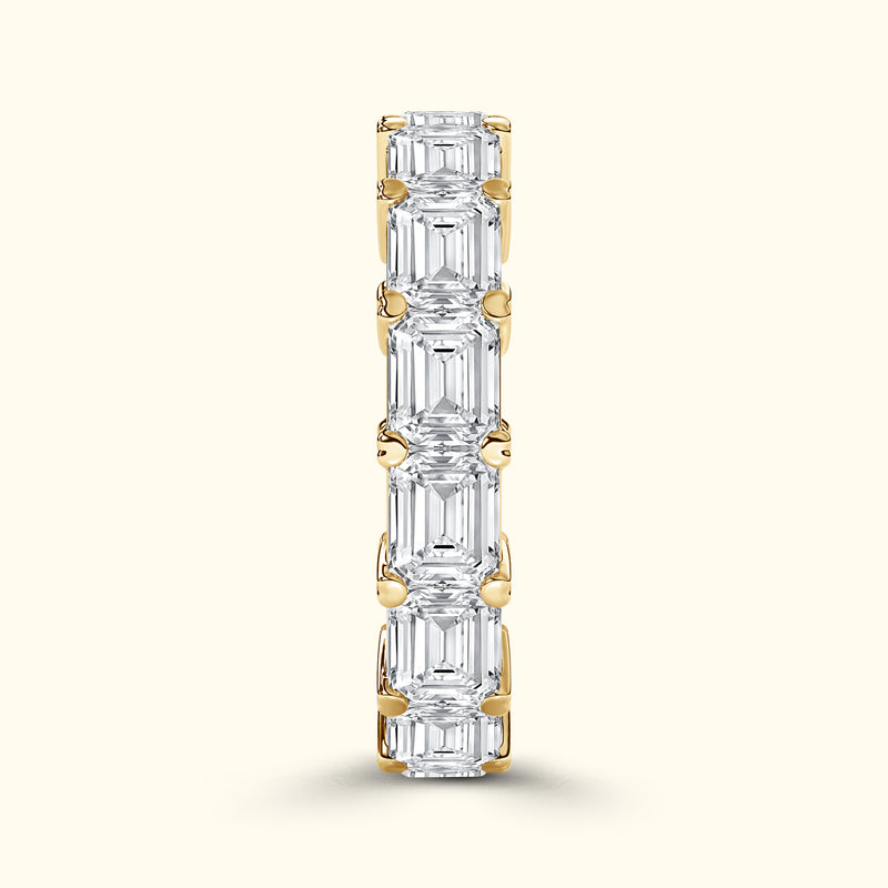 Gold band set with alternating emerald-cut diamonds, vertically oriented.