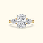 Gold ring featuring a large oval diamond center stone and two side pear-shaped diamonds.