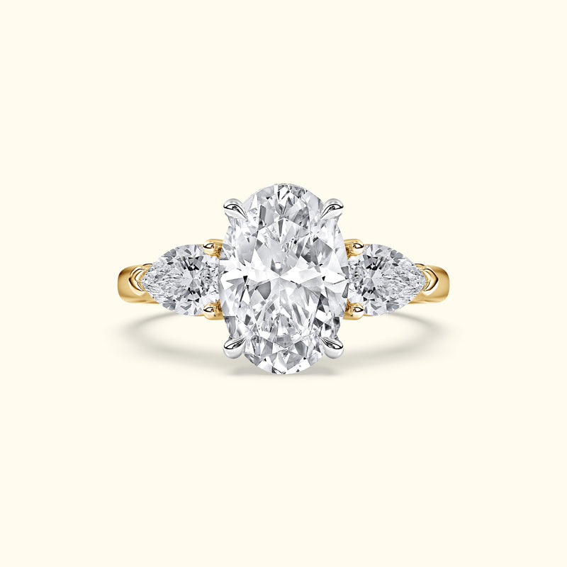 Oval diamond engagement ring with two side stones, set in a gold band.
