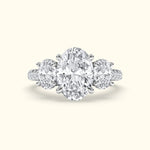 Three-stone diamond ring featuring an oval center stone and two round side stones.