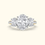Three-stone engagement ring featuring a large oval diamond center with two round diamonds on each side.