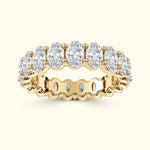 Gold band ring set with multiple oval-shaped, sparkling clear gemstones.